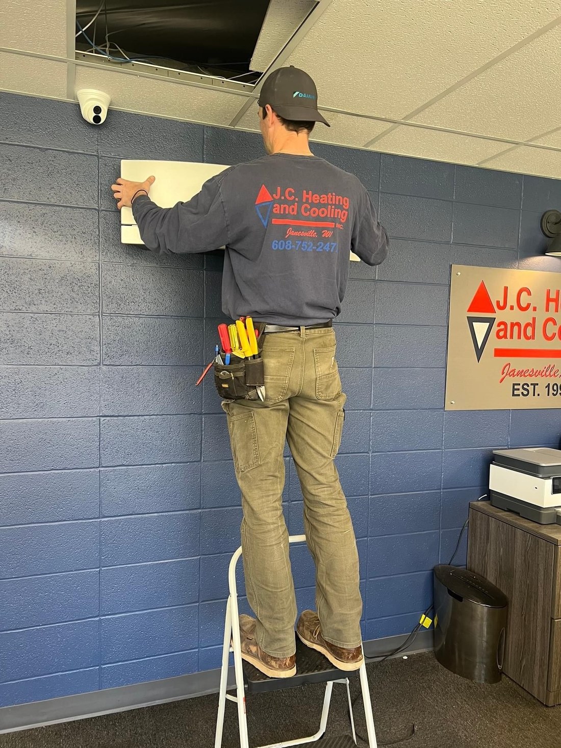 JC technician on a ladder during an installation