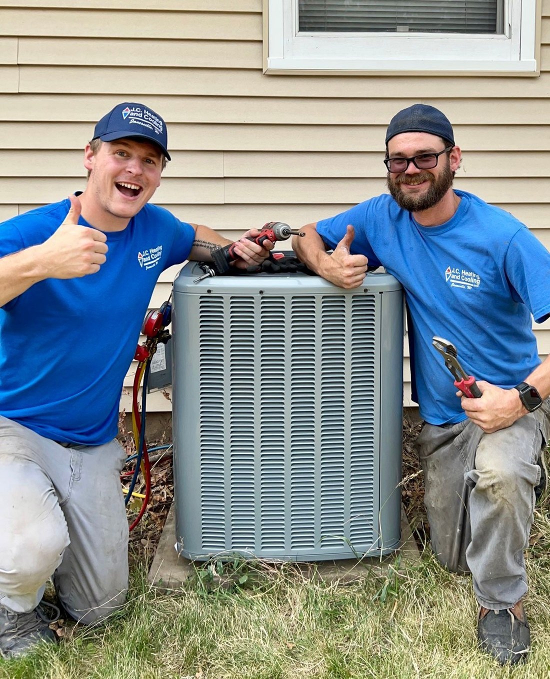 Two JC technicians giving a thumbs up beside a new unit